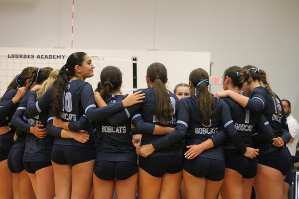 The varsity volleyball team huddles up on the court during their first home game.