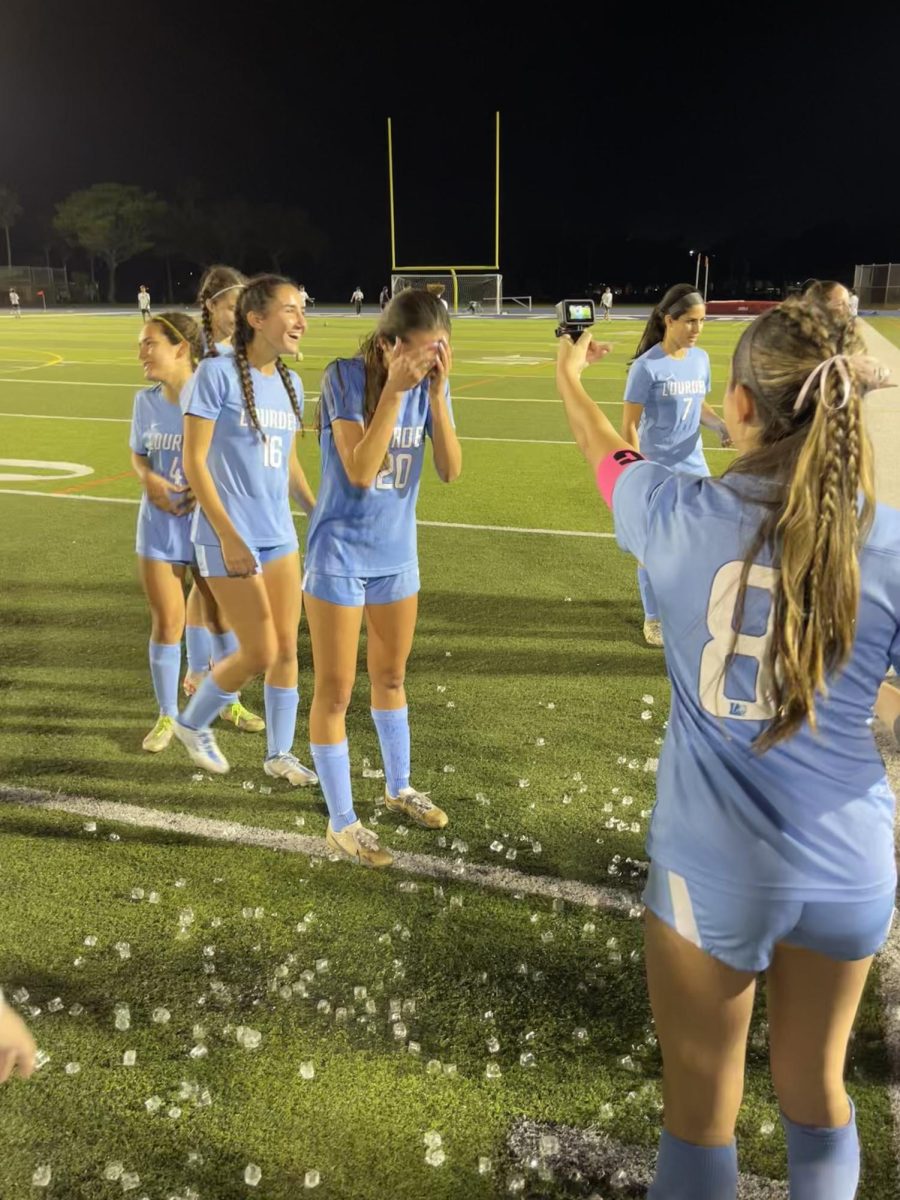 BRING ON THE ICE BUCKET: Following her first goal on varsity, sophomore Katie Tamargo’s teammates chose her to be water buckets next victim. Post game, on the sidelines while Tamargo was taking a sophomore picture, junior Mia Roca and senior Alex Diaz crept up behind her and poured the ice cold water over her head. “I did not expect them to pour that bucket over my head but when they did I ran as fast as I could. The water was absolutely freezing and it didn’t help that it was 65° but it was a funny moment and I loved it,”  Tamargo said.  