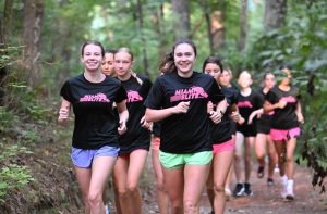 Co-captains Cristina Sanchez and Olivia Rodriguez run through a trail in the woods during training.